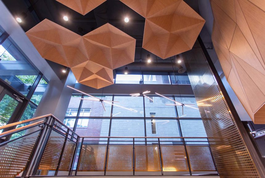 This open area has wood colored hexagonal panels. There are large windows and brown railings. 