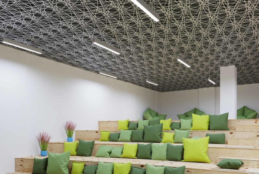This conference room has wood bench seating, plants, green pillows and white walls. 