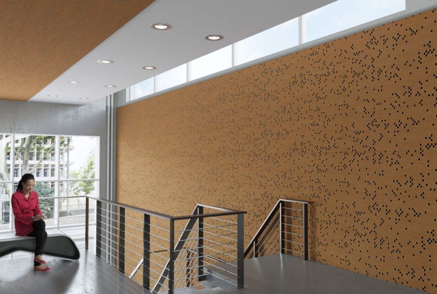 This hallway has wood panels on the walls. There is a person sitting on a bench next to the stairway. 