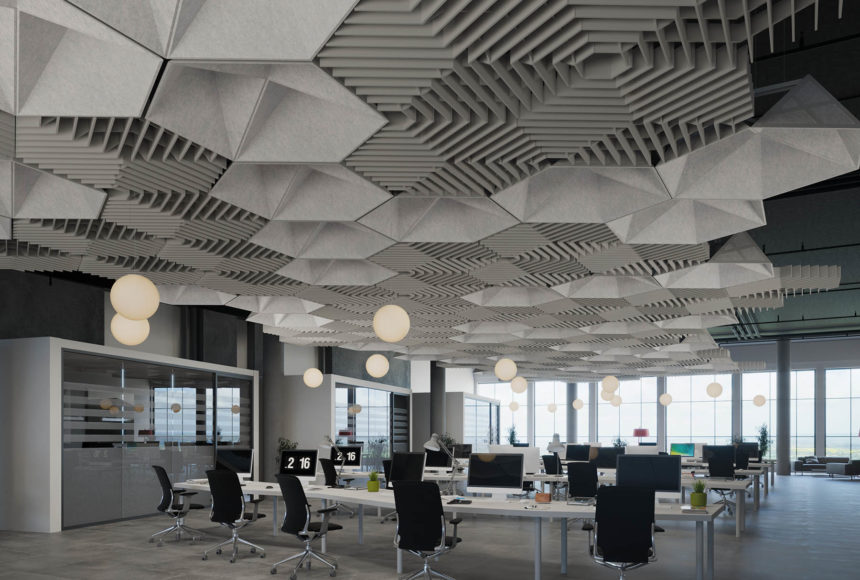 This office space has hexagonal ceiling panels in a light gray color. The desk areas have black and silver chairs. There are sphere-shaped hanging light fixtures. 