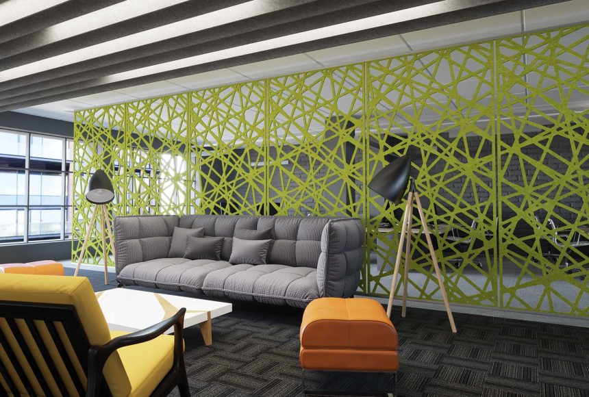 This seating area features a gray sofa, an orange ottoman, a white coffee table and a yellow chair. There is a green screen behind the sofa that allows people to look into the adjacent space while separating the two work areas. 