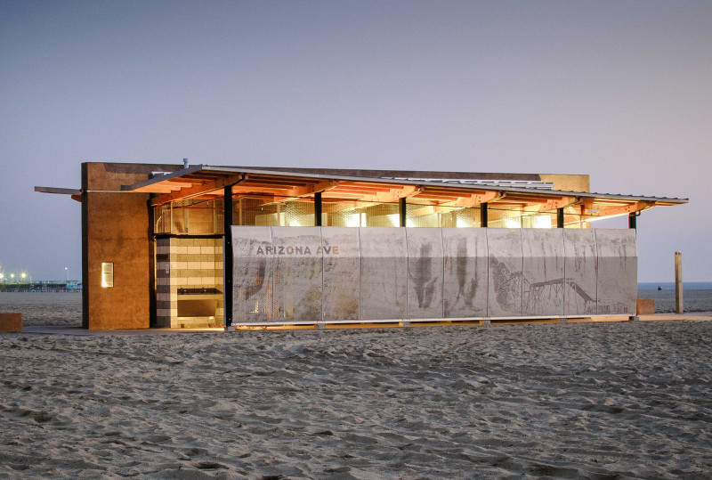 This image shows a building with bathrooms in Santa Monica Beach. There is detailed imagery on the outside of the bathrooms, and “Arizona Ave” is spelled out on the siding.