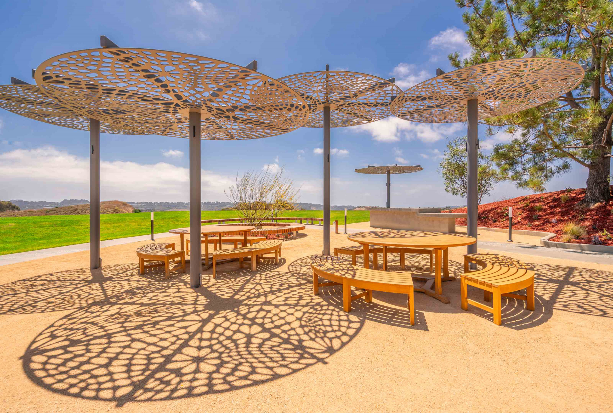 This outdoor area with tables and chairs features several Arktura canopies that resemble umbrellas above the tables. 
