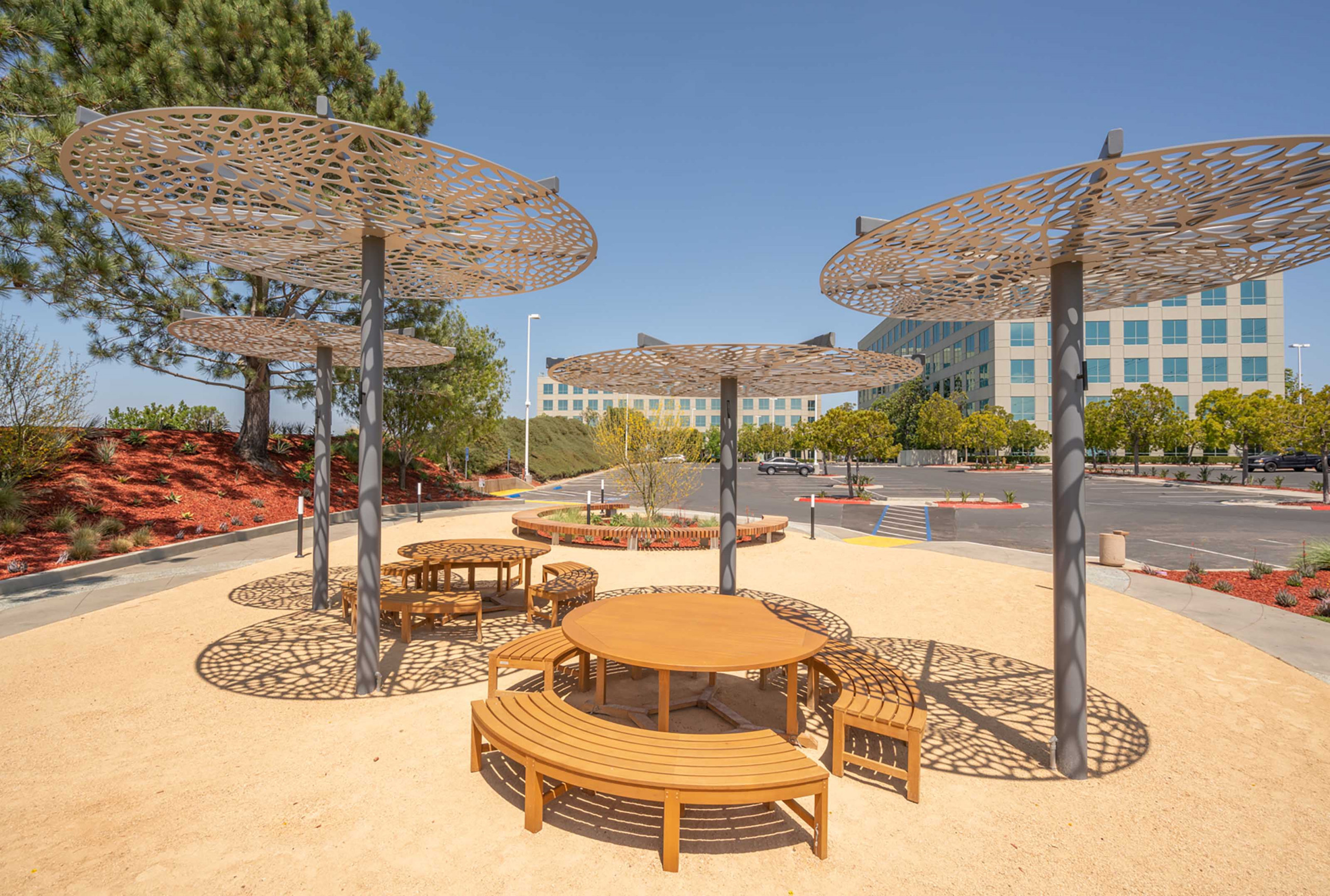 This outdoor area with tables and chairs features several Arktura canopies that resemble umbrellas above the tables. 