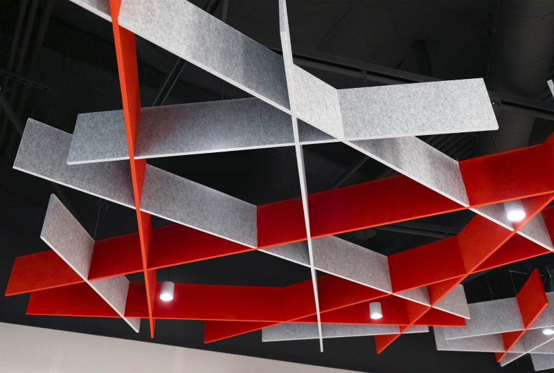 Acoustic drop ceilings shown in red and grey with small can lights shining through the soft sound material.