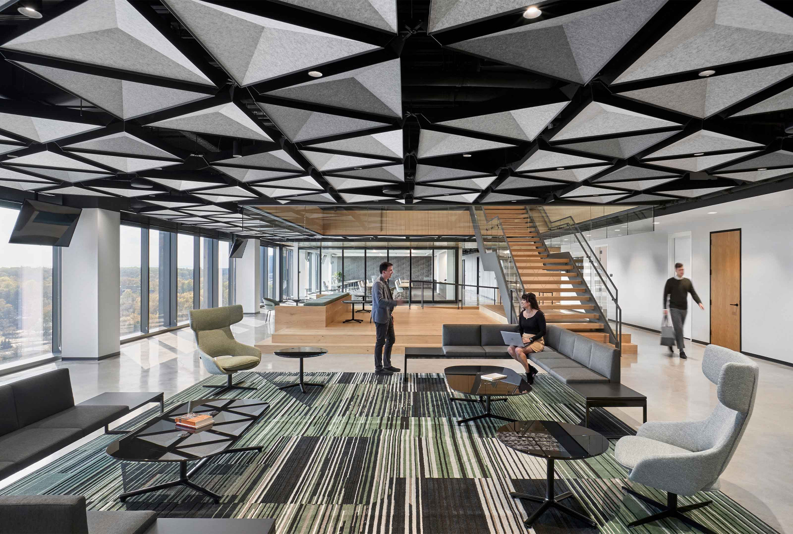An office lobby with three employees, showcasing Arktura’s TriSoft triangular faceted pyramid faces in light grey with black metal substructure.